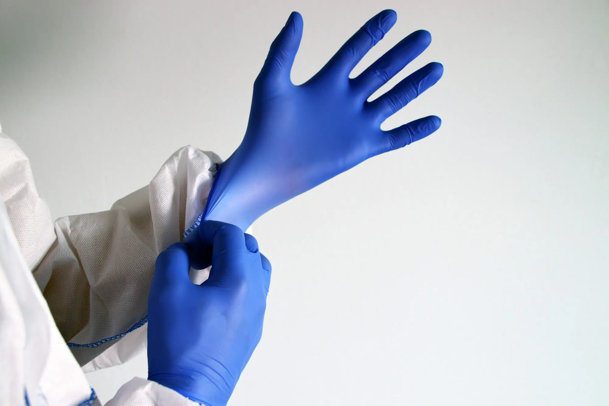 Person pulling on a blue nitrile glove