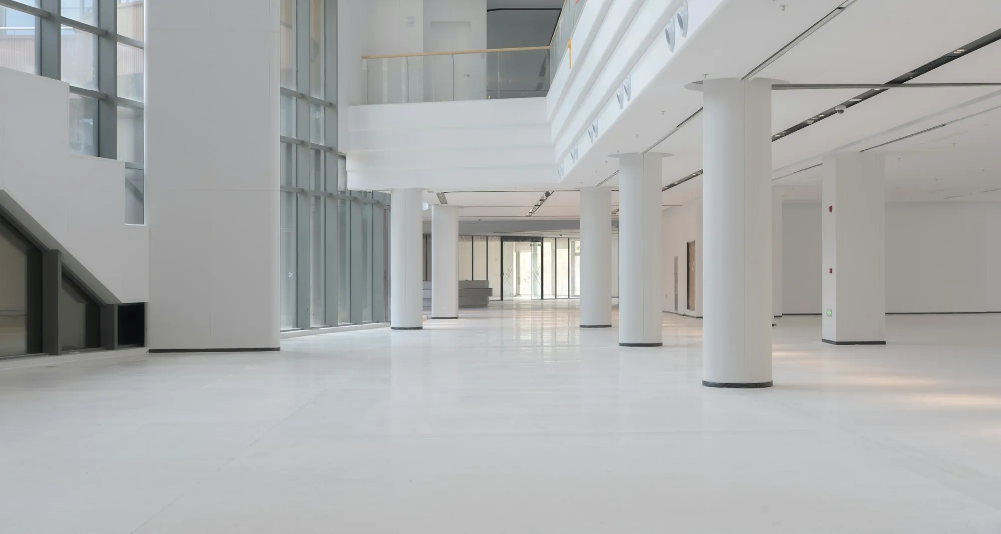 Bright, empty office atrium with white columns and polished floors